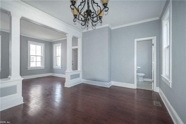 unfurnished dining area with decorative columns, crown molding, dark wood-type flooring, and a chandelier