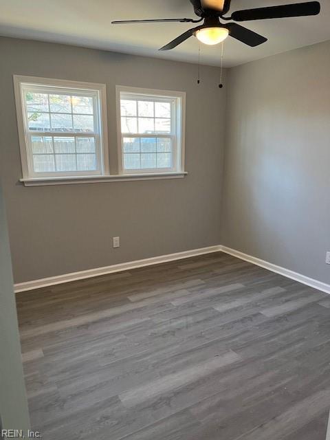 spare room featuring plenty of natural light, ceiling fan, and dark hardwood / wood-style flooring