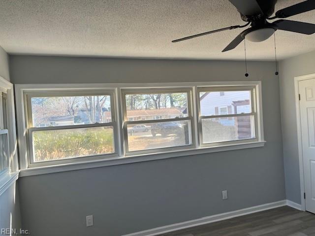 spare room featuring dark hardwood / wood-style floors, a healthy amount of sunlight, and a textured ceiling