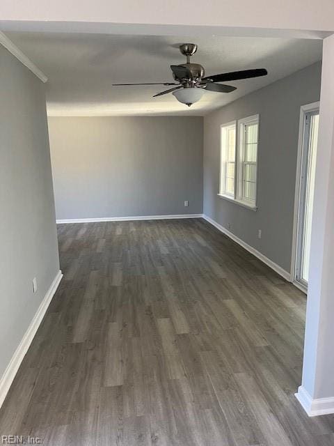 empty room featuring ceiling fan, ornamental molding, and dark wood-type flooring