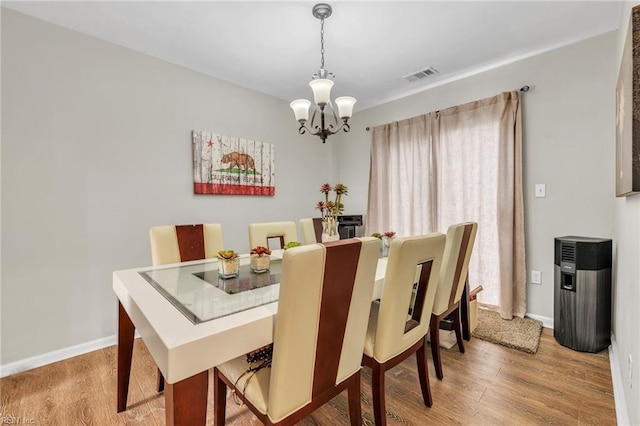 dining space featuring wood-type flooring and an inviting chandelier