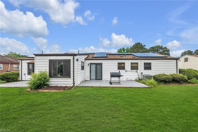 rear view of house featuring solar panels, a yard, and a patio area