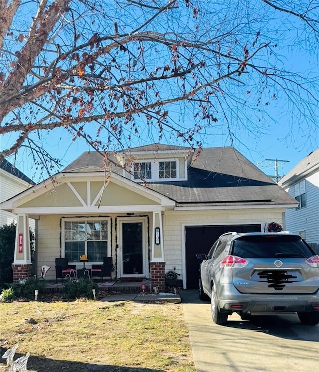 view of front of home with covered porch, a front lawn, and a garage