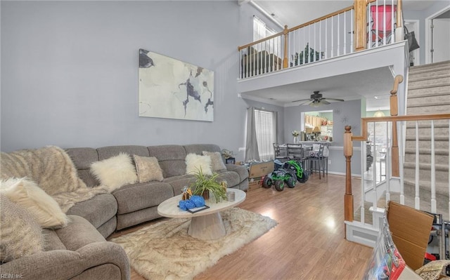 living room with ceiling fan, hardwood / wood-style floors, and a towering ceiling