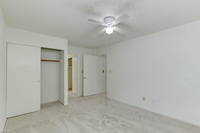 unfurnished bedroom with a textured ceiling, a closet, ceiling fan, and light colored carpet