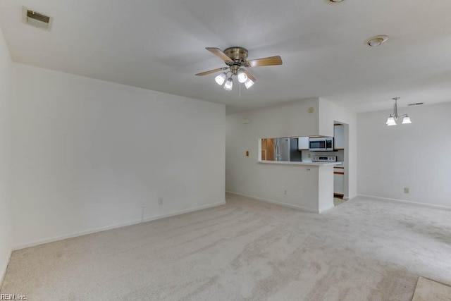 unfurnished living room with ceiling fan with notable chandelier and light colored carpet