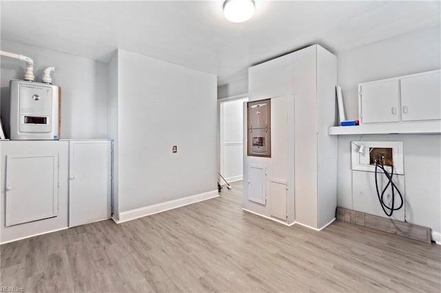 washroom featuring light wood-type flooring, hookup for a washing machine, and water heater