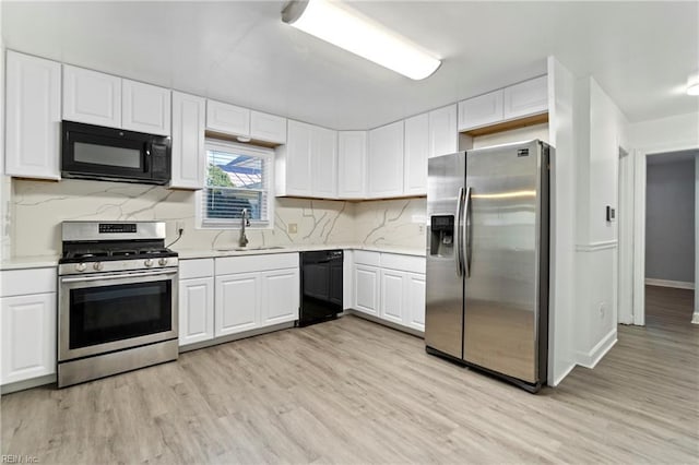 kitchen featuring backsplash, sink, black appliances, light hardwood / wood-style flooring, and white cabinetry