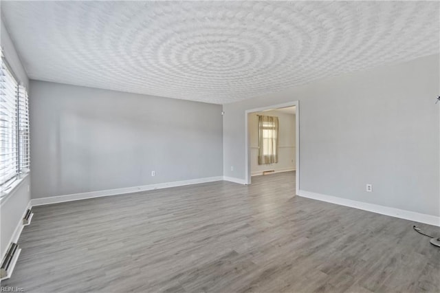 empty room with plenty of natural light and hardwood / wood-style floors