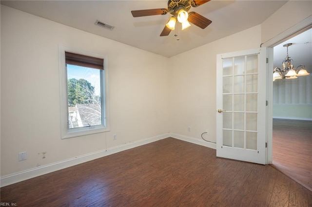 empty room with lofted ceiling, ceiling fan with notable chandelier, and dark wood-type flooring