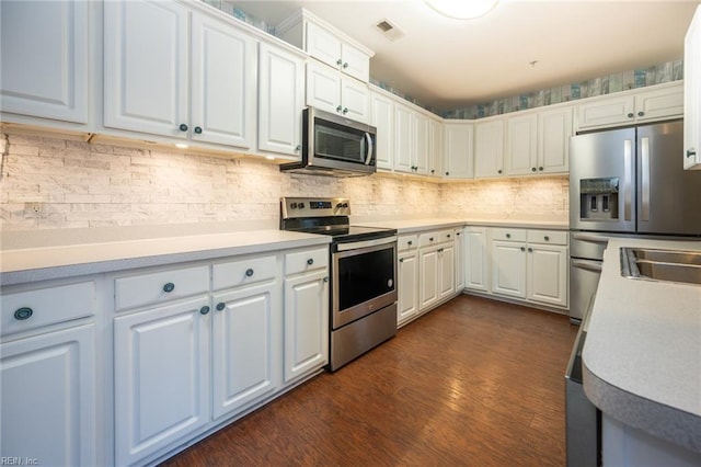 kitchen featuring white cabinets, appliances with stainless steel finishes, backsplash, and dark hardwood / wood-style floors