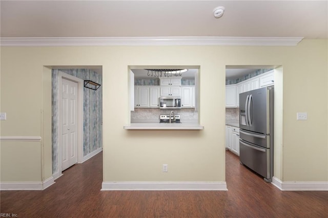 kitchen with backsplash, stainless steel appliances, white cabinetry, and ornamental molding