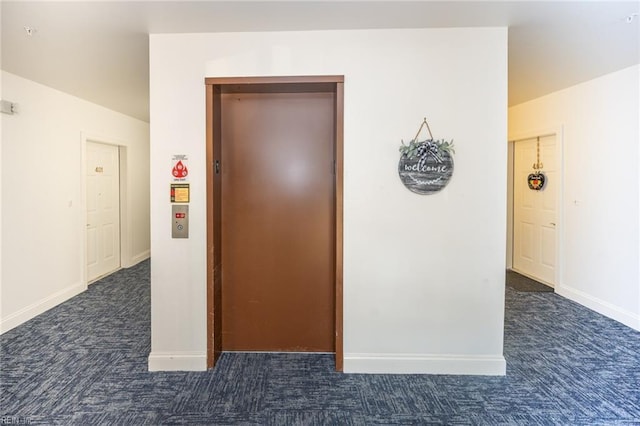 corridor with dark colored carpet and elevator