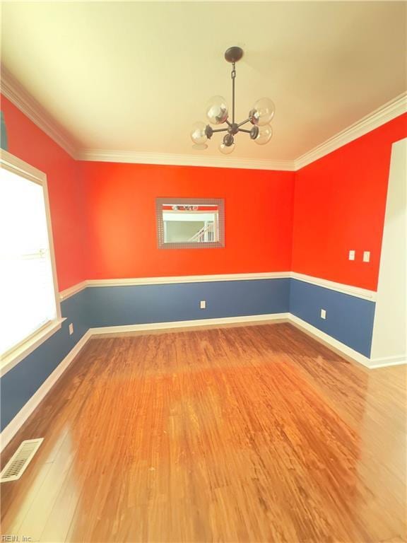 empty room featuring an inviting chandelier, hardwood / wood-style flooring, and ornamental molding