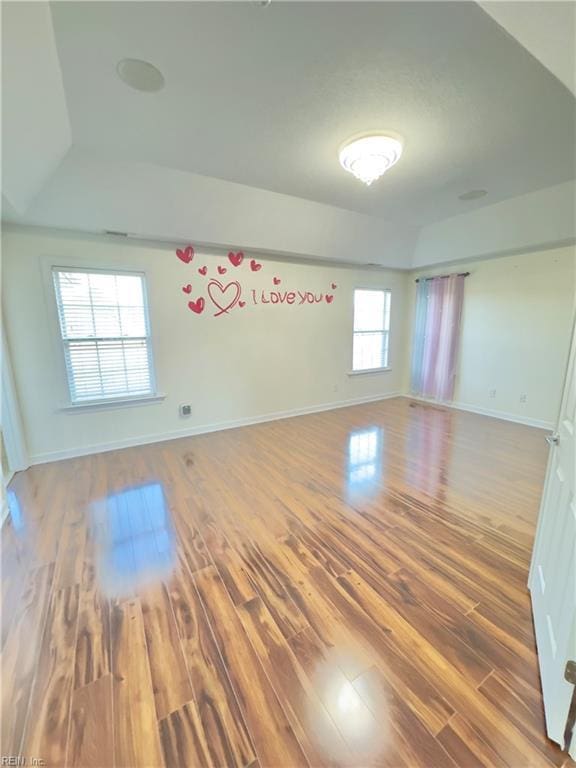 empty room featuring hardwood / wood-style flooring, a wealth of natural light, and lofted ceiling