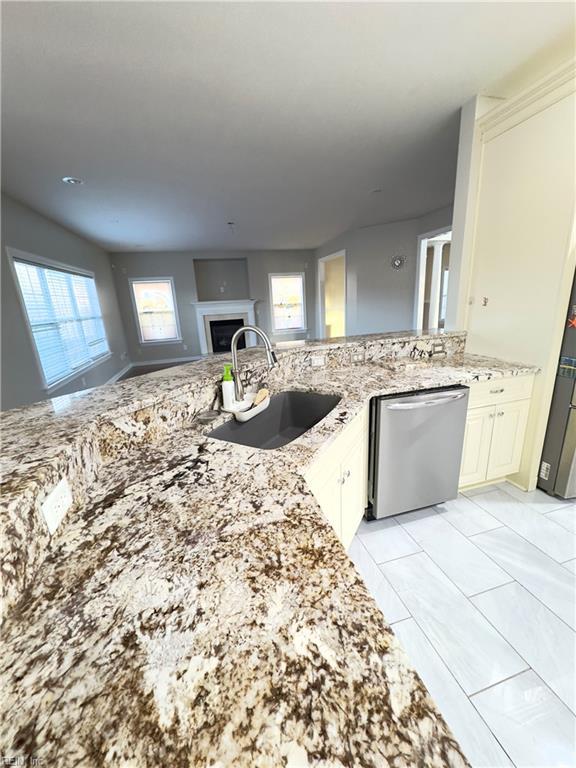 kitchen with sink, light tile patterned floors, dishwasher, and light stone counters