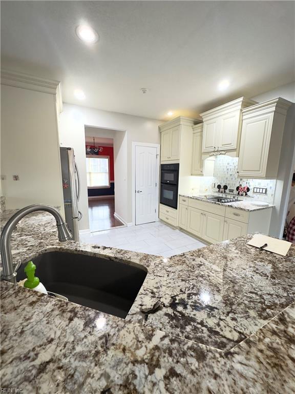 kitchen with sink, cream cabinets, backsplash, and stainless steel fridge