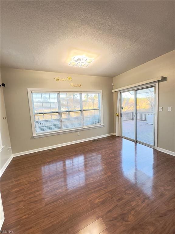 empty room with a textured ceiling and dark hardwood / wood-style floors