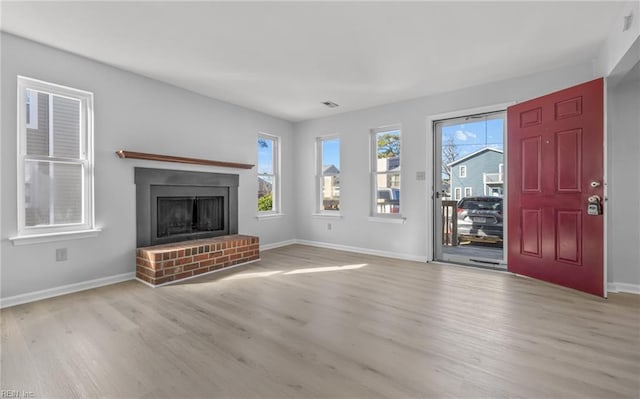 unfurnished living room with a wealth of natural light, a fireplace, and light hardwood / wood-style flooring