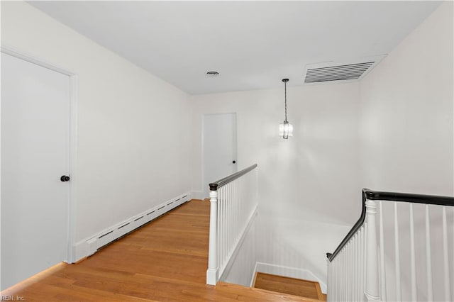 staircase featuring wood-type flooring and a baseboard heating unit