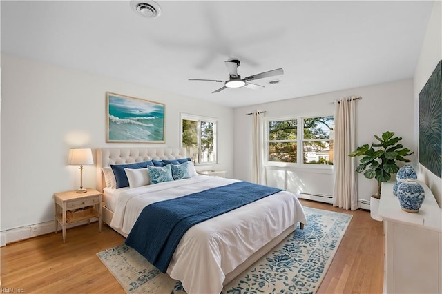 bedroom with ceiling fan, light hardwood / wood-style flooring, and a baseboard heating unit