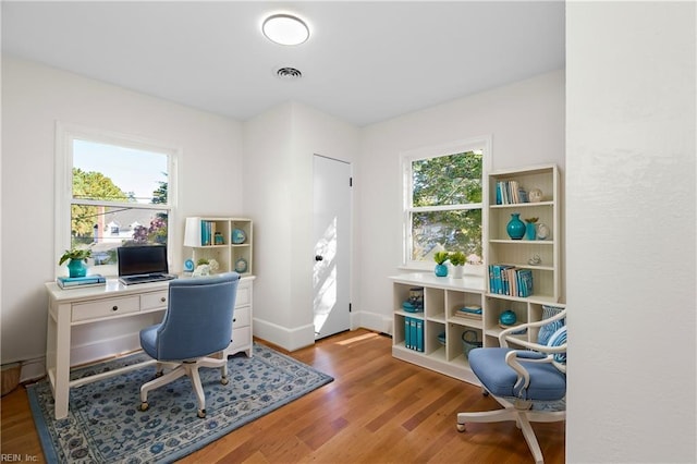 home office with plenty of natural light and hardwood / wood-style flooring