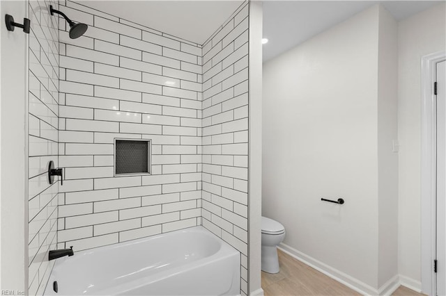 bathroom with hardwood / wood-style flooring, tiled shower / bath combo, and toilet