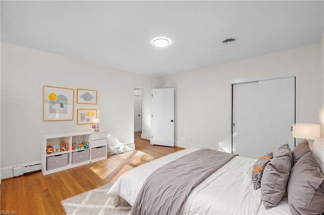 bedroom with hardwood / wood-style flooring, a closet, and a baseboard radiator