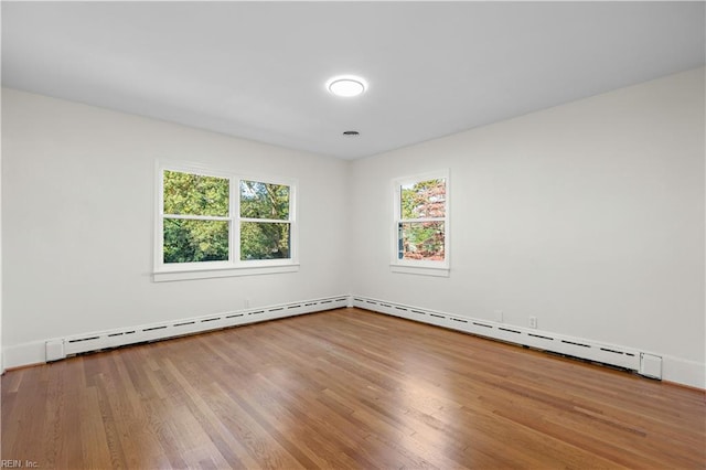 unfurnished room with baseboard heating and wood-type flooring