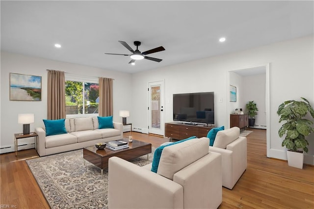 living room featuring baseboard heating, light hardwood / wood-style flooring, and ceiling fan