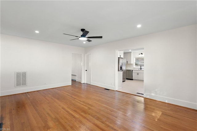 unfurnished room with ceiling fan, light hardwood / wood-style floors, and radiator heating unit