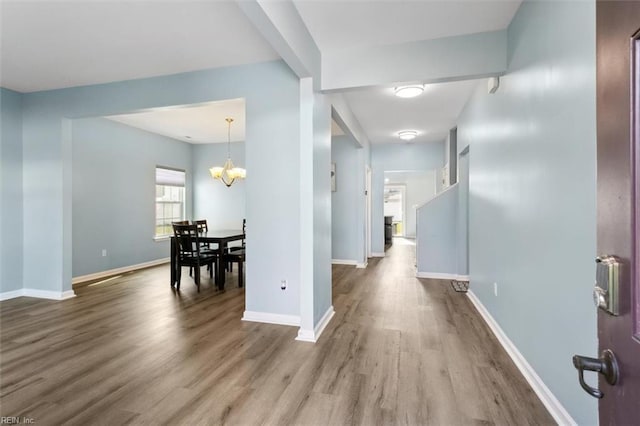 corridor with hardwood / wood-style floors and a chandelier