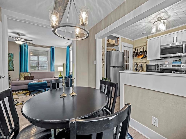 dining area with ceiling fan with notable chandelier, light wood-type flooring, and ornamental molding