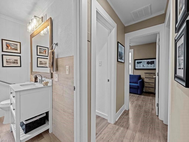 hall featuring light hardwood / wood-style floors, ornamental molding, and sink