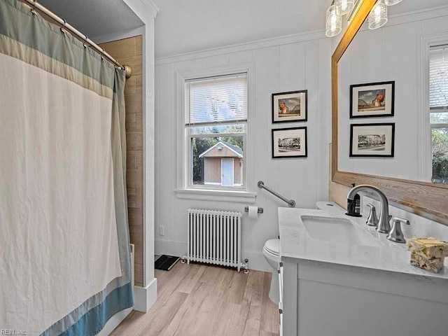 bathroom featuring radiator, ornamental molding, vanity, hardwood / wood-style flooring, and toilet