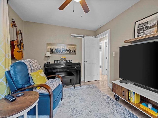 living area with a barn door, light hardwood / wood-style floors, and ceiling fan