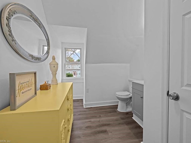 bathroom with hardwood / wood-style flooring, vanity, toilet, and lofted ceiling