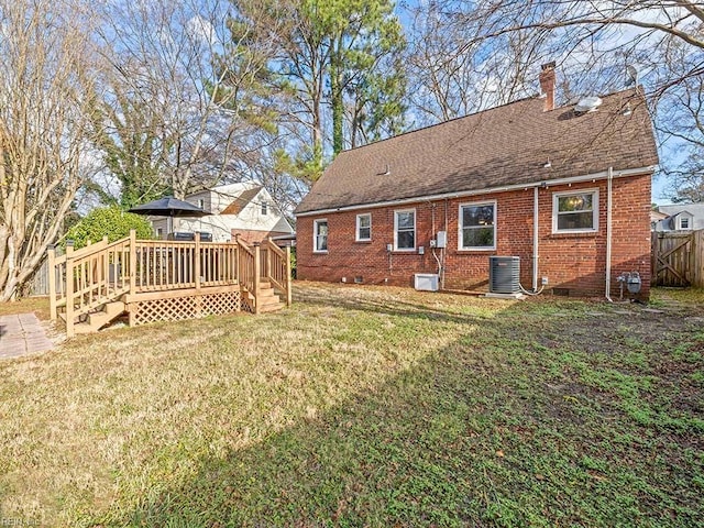 rear view of house with a deck, central AC unit, and a lawn