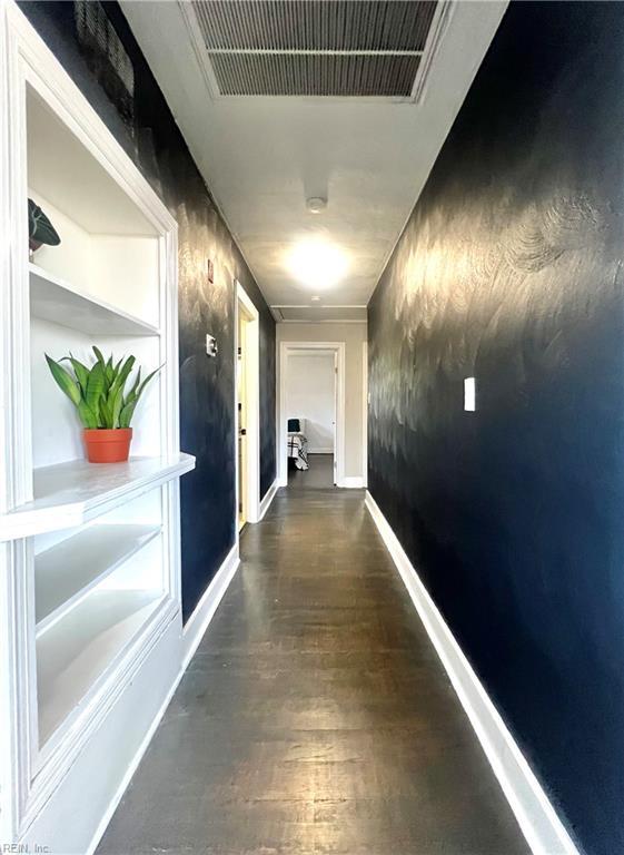 corridor featuring built in shelves and dark wood-type flooring