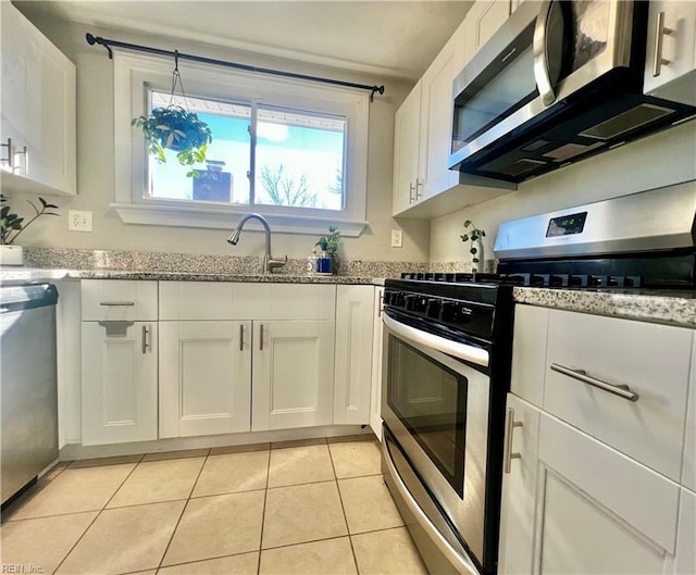 kitchen with white cabinets, sink, light tile patterned floors, appliances with stainless steel finishes, and light stone counters