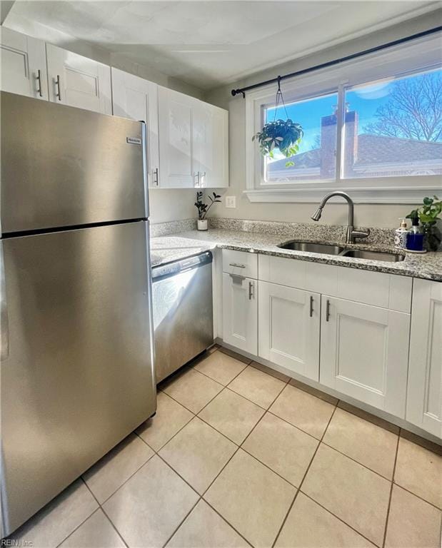 kitchen with sink, white cabinetry, stainless steel appliances, and light tile patterned floors