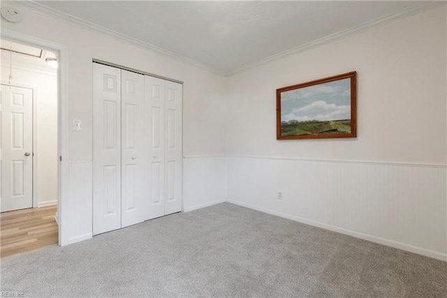 unfurnished bedroom with a closet, light colored carpet, and ornamental molding