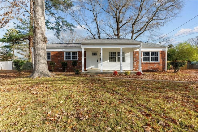 ranch-style house featuring covered porch and a front yard