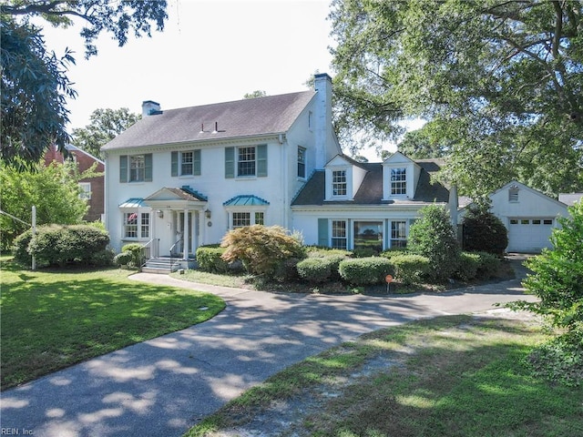 colonial house featuring an outdoor structure, a front yard, and a garage