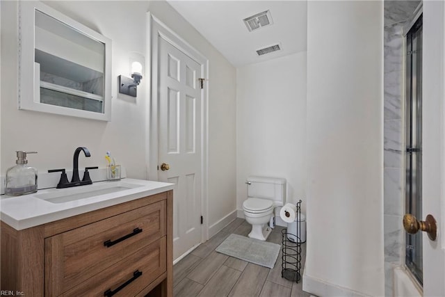 bathroom featuring vanity, toilet, and a shower with door