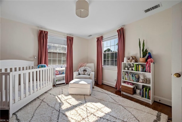 bedroom with wood-type flooring and a nursery area