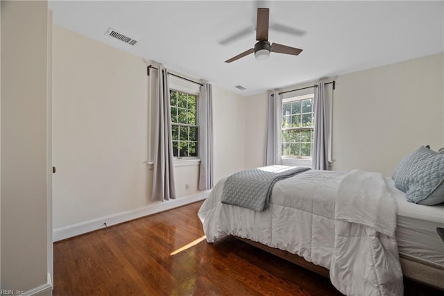 bedroom with multiple windows, dark hardwood / wood-style flooring, and ceiling fan