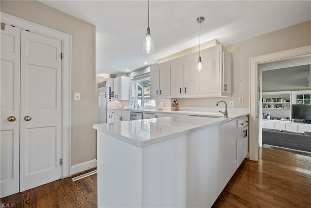 kitchen with pendant lighting, white cabinets, sink, built in features, and kitchen peninsula