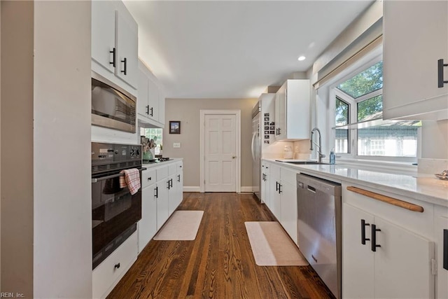 kitchen with built in appliances, dark hardwood / wood-style flooring, white cabinets, and sink