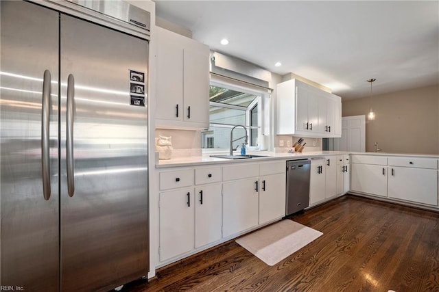 kitchen featuring white cabinets, stainless steel appliances, hanging light fixtures, and sink